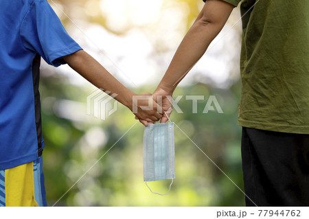 Two mothers hold hands and have a mask in both hands, concept of public prevention of respiratory disease or COVID-19. Two mothers hold hands and have a mask in both hands, concept of public prevention of respiratory disease or COVID-19. 77944762