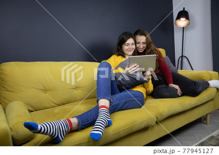 young lesbian couple make purchases or payments online lying on sofa 77945127