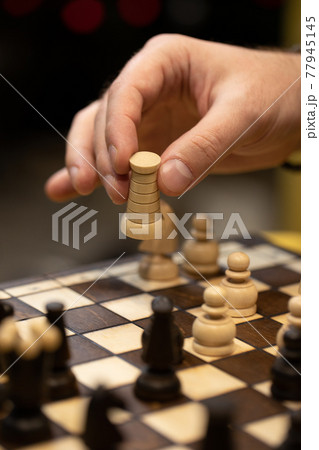 Hand taking next step on chess game. Human hand moving wooden white rook piece 77945145