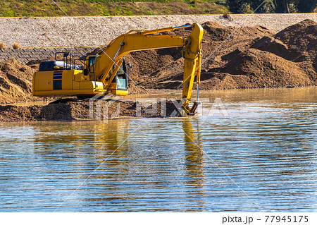 川底の土砂をすくう油圧ショベル 77945175