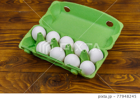 Raw chicken eggs in cardboard egg box with empty space on wooden table Raw chicken eggs in cardboard egg box with empty space on wooden table 77948245