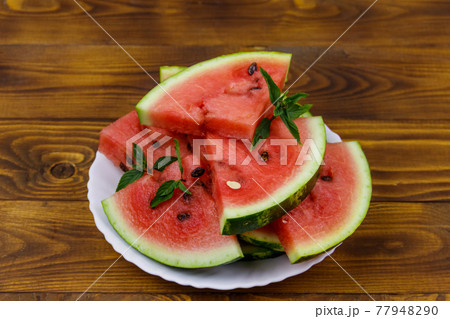 Fresh ripe sliced watermelon in white plate on a wooden table Fresh ripe sliced watermelon in white plate on a wooden table 77948290