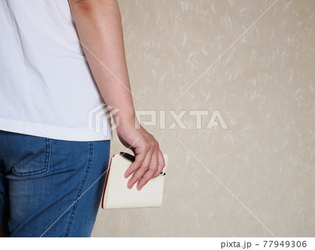 手にノートとペンを持ったラフな服装の女性の写真素材