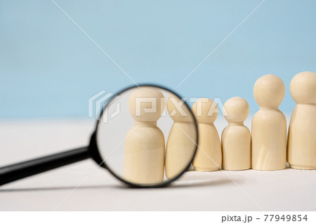 Wooden figures of people under magnifying glass on blue background. 77949854
