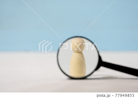 Wooden figures of people under magnifying glass on blue background. Wooden figures of people under magnifying glass on blue background. 77949855