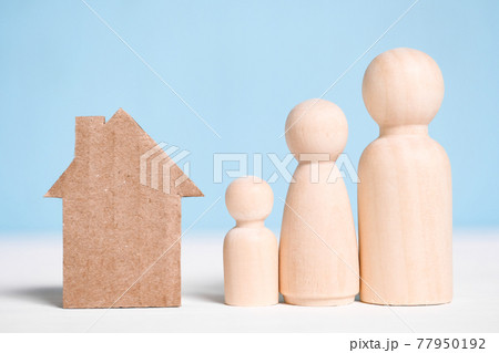 Wooden figures family with cardboard house on blue background. 77950192
