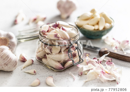 Rustic jar filled up with aromatic garlic cloves on the white desk Rustic jar filled up with aromatic garlic cloves on the white desk 77952806