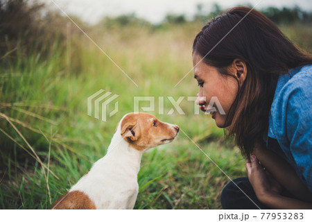 Happy cheerful hipster girl playing with her dog in the park during sunset. Vintage of young woman with her dog. Happy cheerful hipster girl playing with her dog in the park during sunset. Vintage of young woman with her dog. 77953283