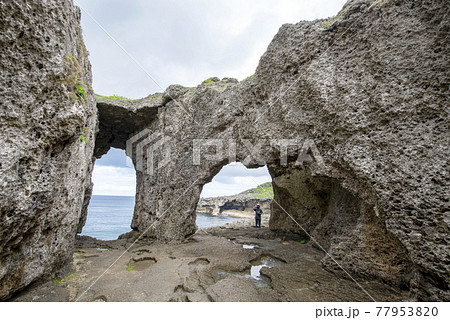 徳之島の天城町の犬の門蓋のメガネ岩で動画撮影する女性フォトグラファー 77953820