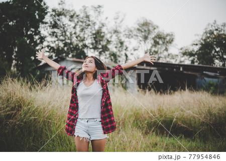 Young beautiful woman enjoying nature in field. Woman raising her arm up in the air enjoy with mature. Women lifestyle with vintage filter. Young beautiful woman enjoying nature in field. Woman raising her arm up in the air enjoy with mature. Women lifestyle with vintage filter. 77954846