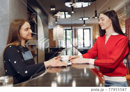 Woman sitting in a cafe and talking with barista Woman sitting in a cafe and talking with barista 77955587