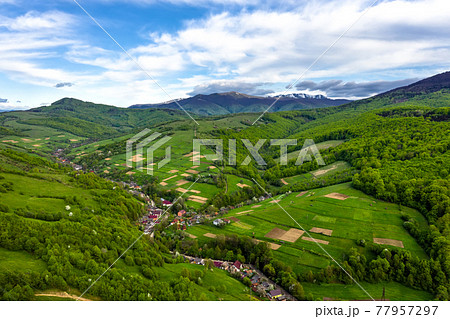 Snow-capped mountain peaks and beautiful forest mountains in summer aerial view. 77957297