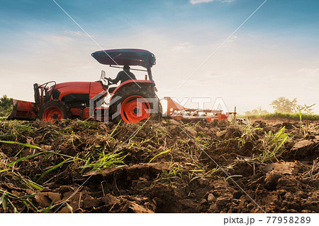 Farmer with tractor prepares the land to grow agricultural crops. Farmer with tractor prepares the land to grow agricultural crops. 77958289