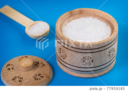 Salt in a wooden salt shaker on blue background Salt in a wooden salt shaker on blue background 77959183