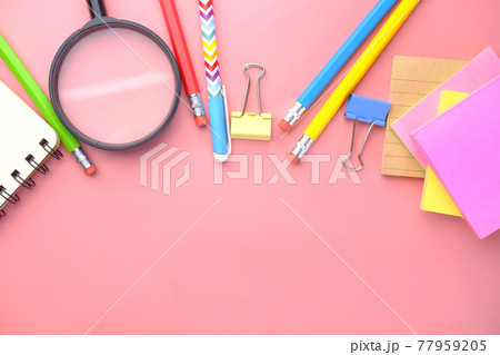 magnifying glass and stationery on pink  77959205