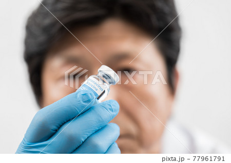 新型コロナウイルスワクチンを見つめる男性医師 77961791