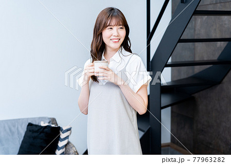 リビングでコーヒーを飲みながら寛ぐ女性 リビングでコーヒーを飲みながら寛ぐ女性 77963282