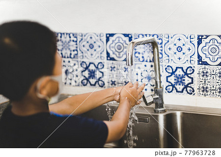 Asian little boy hand washing with tap water in kitchen sink during covid-19. 77963728