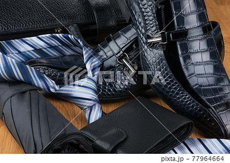 Close-up of men's fashion accessories. Umbrella and tie, shoes and wallet on the background of a leather briefcase. 77964664