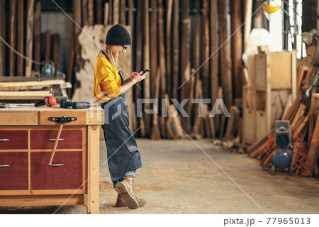 Female joiner using smartphone in workshop 77965013