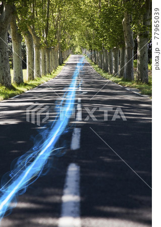 Blue streak of light on country road along trees 77965039