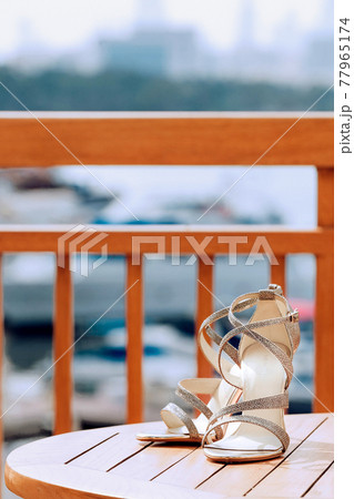 Golden sandals with heels of the bride, stand on a wooden surface 77965174