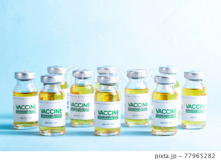 Coronavirus vaccine dose bottles on blue background covered in smoke. Kotsnept developing and testing a new vaccine in the laboratory Coronavirus vaccine dose bottles on blue background covered in smoke. Kotsnept developing and testing a new vaccine in the laboratory 77965282