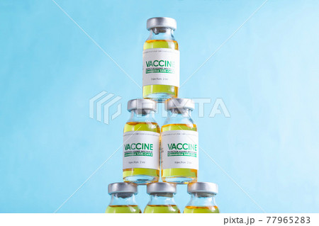 Vials of coronavirus vaccine doses are arranged in a pyramid on a blue background. Vaccine research and development concept covid-19, 77965283