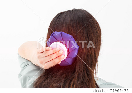 A girl holds a blue ice bag near her head to eliminate pain in the head, lowering blood pressure in case of arterial hypertension and stress, close-up A girl holds a blue ice bag near her head to eliminate pain in the head, lowering blood pressure in case of arterial hypertension and stress, close-up 77965472