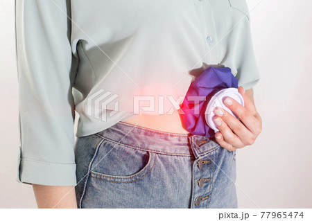 The girl applies cold in a medical bag to relieve abdominal pain and pain relief. The concept of cold compresses for lubricants and abdominal pain, close-up The girl applies cold in a medical bag to relieve abdominal pain and pain relief. The concept of cold compresses for lubricants and abdominal pain, close-up 77965474