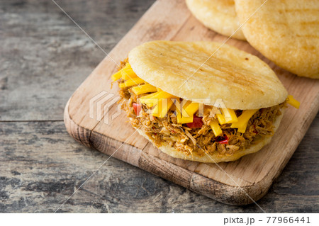 Arepa with shredded beef and cheese on wooden background. 77966441