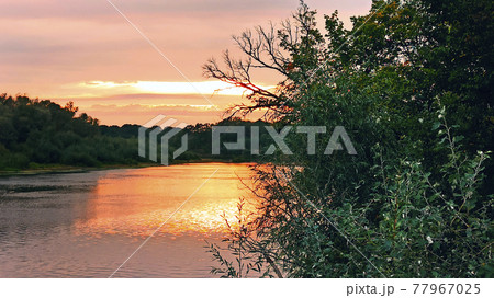 Beautiful blazing sunset landscape above river and orange sky in evening Beautiful blazing sunset landscape above river and orange sky in evening 77967025