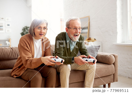 Excited senior couple playing video console games at home 77969511