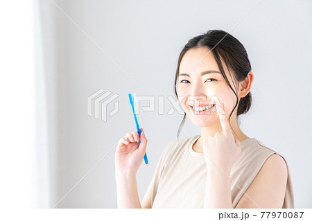 歯ブラシを持ちながら指差す若い女性 歯ブラシを持ちながら指差す若い女性 77970087