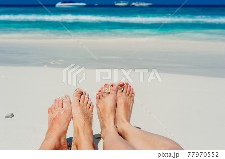 Young woman looking down of view perspective on bare feet standing in white sand Young woman looking down of view perspective on bare feet standing in white sand 77970552