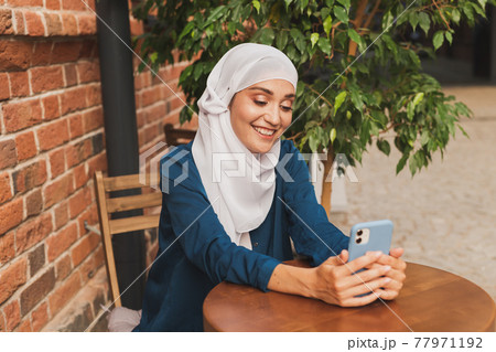 Happy muslim woman having video call on smartphone in city Happy muslim woman having video call on smartphone in city 77971192