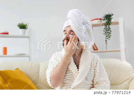 Bearded man applying eye patches on his face. Wrinkles and face home care for men. Bearded man applying eye patches on his face. Wrinkles and face home care for men. 77971214
