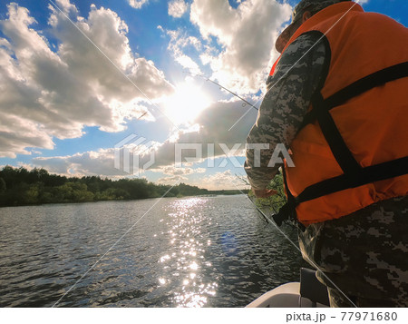 fisherman with fishing rod and river at sunset 77971680