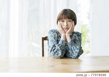 頬杖をついた困った表情の若い女性 77978096