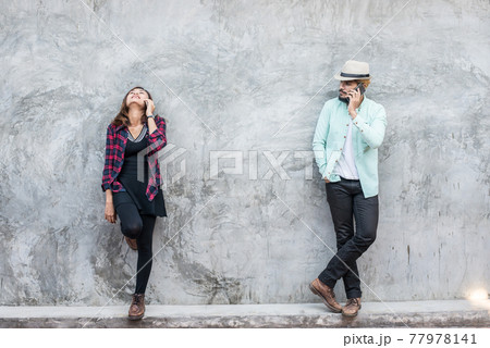 Couple talking to mobile on brick wall, vintage, grunge background. 77978141