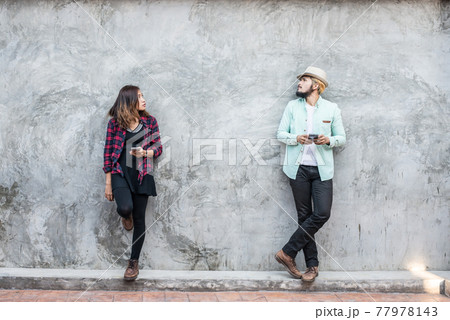 Couple talking to mobile on brick wall, vintage, grunge background. Couple talking to mobile on brick wall, vintage, grunge background. 77978143