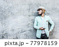 Portrait of handsome young hipster man listening to music against a grunge bricks wall background. 77978159