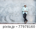 Portrait of handsome young hipster man listening to music against a grunge bricks wall background. 77978160