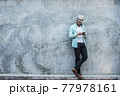 Portrait of handsome young hipster man listening to music against a grunge bricks wall background. 77978161