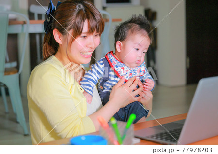 テレワークの母親とpcを凝視する乳児2の写真素材