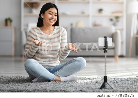Young Asian Woman Using Smartphone On Tripod For Recording Video At Home 77980878