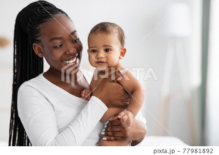 African American nanny hugging her cute infant and posing 77981892
