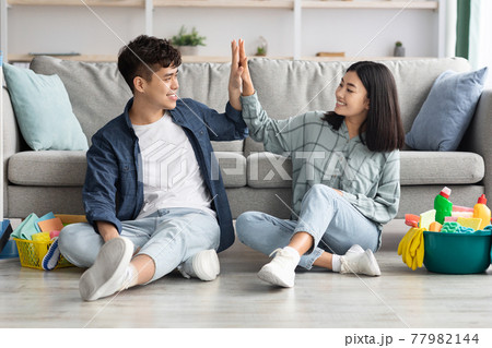 Tired asian couple sitting on floor, giving high five Tired asian couple sitting on floor, giving high five 77982144