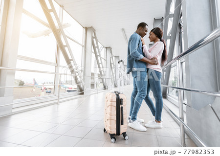 Couple In Airport. Romantic Black Lovers Embracing In Terminal Corridor Couple In Airport. Romantic Black Lovers Embracing In Terminal Corridor 77982353