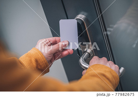 Bearded young man opening the door with an access card 77982675